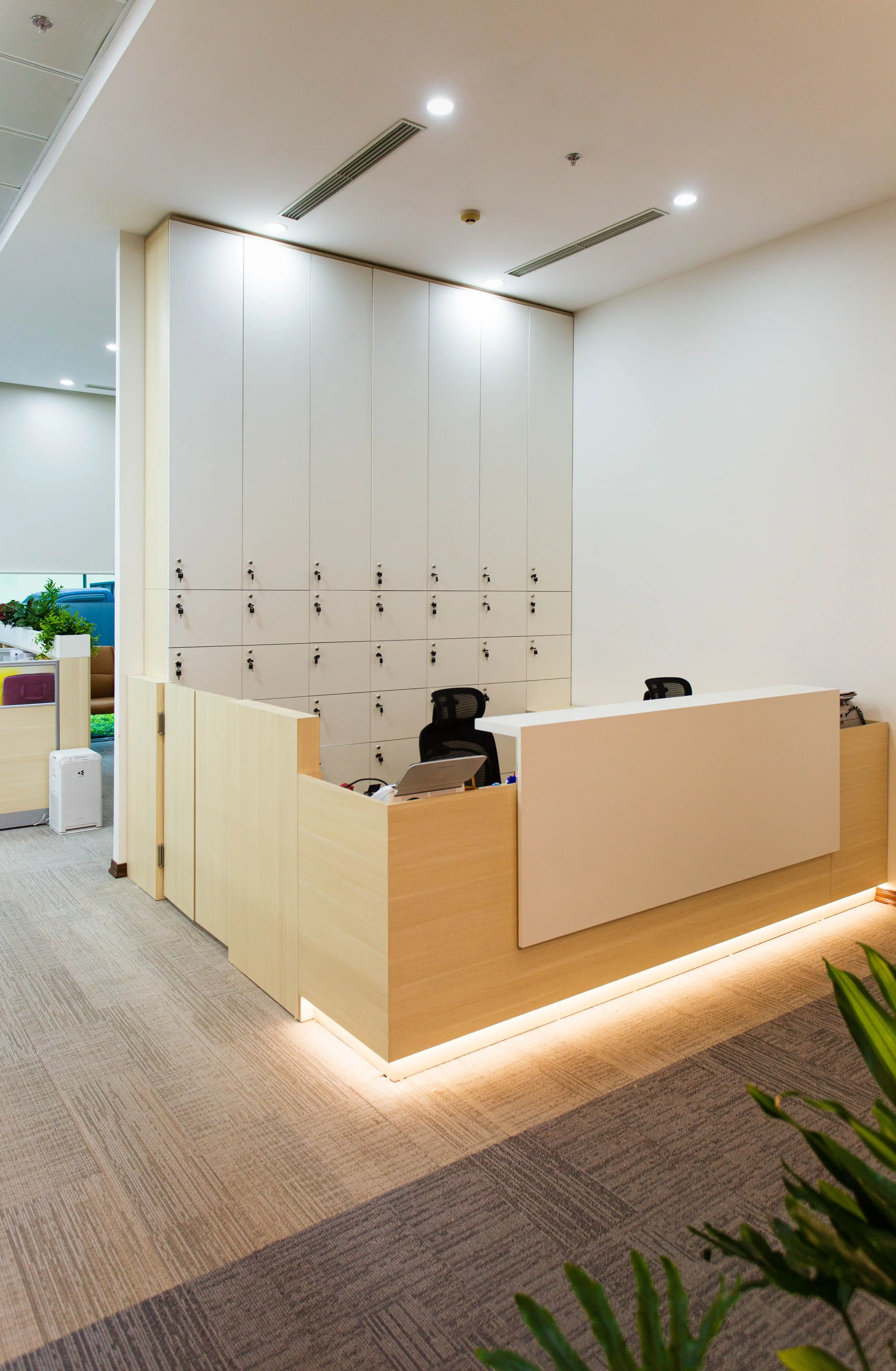 Modern office lounge with oak reception desk, moss wall, and soft seating